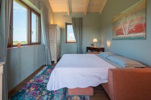 a bedroom with a bed and a couch and windows at I Quattro Pozzi in La Morra