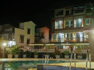 a hotel with a swimming pool in front of a building at The Tree Resort in Malavli