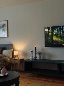 a living room with a couch and a tv on the wall at The Garden room in Ikšķile