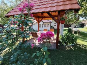 a wooden gazebo with a bench and pink flowers at Verina kuća in Kosjeric +56 photos