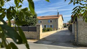 a house with a brick wall and a street at Chambres d'hôtes Les Rozières in Le Bourdet