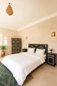 a bedroom with a large white bed with two tables at Dar Benyahya in Aït Zat