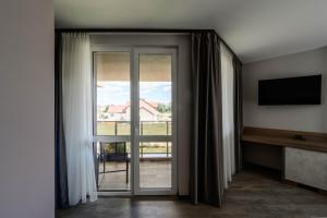 a room with a sliding glass door with a television at Vital Hotel in Sofia