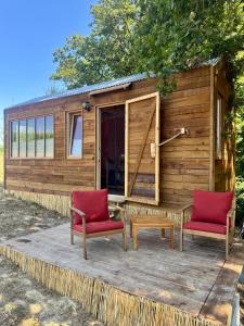 a tiny house with two chairs and a table at Tiny House en lisière de bois in Bastennes