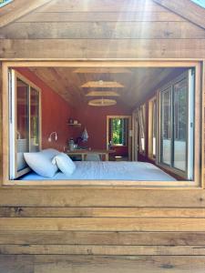 a bedroom with a large bed with a large window at Tiny House en lisière de bois in Bastennes