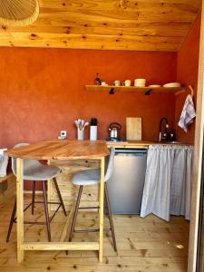 a kitchen with a wooden table and two stools at Tiny House en lisière de bois in Bastennes +12 photos