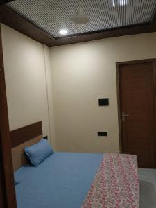 a bedroom with a bed with a blue pillow and a door at Sarovar Home Stay in Vrindāvan