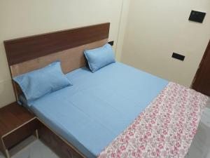 a small bed with a blue bedspread and blue pillows at Sarovar Home Stay in Vrindāvan