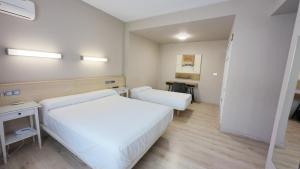 ein Hotelzimmer mit zwei Betten und zwei Tischen in der Unterkunft Hotel Alaiz in Beriáin