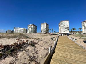 a wooden boardwalk leading to a beach with tall buildings at Costa 010 in Setúbal