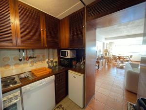 a kitchen with wooden cabinets and a living room at Costa 010 in Setúbal