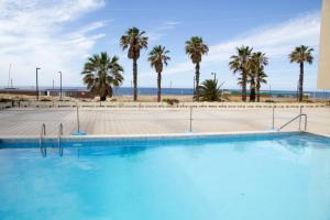 a large swimming pool with palm trees in the background at Costa 010 in Setúbal