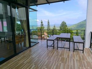 a balcony with a table and benches and a view at Ban Rai Rabeang Mok in Khao Kho