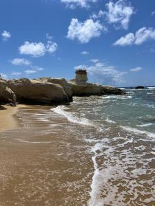 a beach with a rock formation in the water at Pegeia Sun in Peyia
