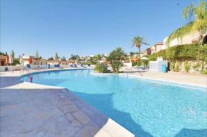 a large swimming pool in a resort with palm trees at Pegeia Sun in Peyia