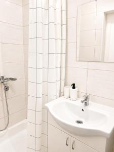 a white bathroom with a sink and a shower at Apartman Lena in Belgrade