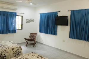 a room with blue curtains and a tv and a chair at Posada Ya´ax Ich in Izamal