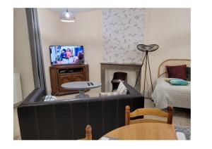 a living room with a tv and a bed at Logis du mont in Saint-Sernin-du-Plain