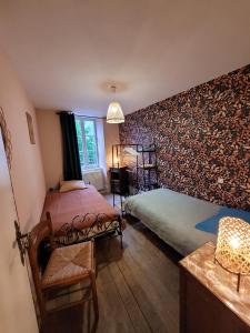 a bedroom with two beds and a wall covered in wallpaper at Logis du mont in Saint-Sernin-du-Plain