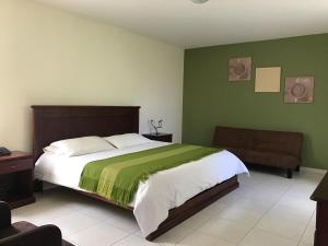 sypialnia z dużym łóżkiem i zielonymi ścianami w obiekcie La Quinta San Andrés w mieście Ibarra