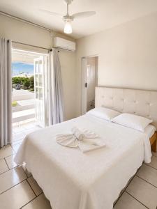 a bedroom with a white bed with a bow on it at Hotel Centro dos Canyons in Praia Grande