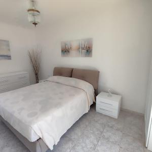 a white bedroom with a bed and a night stand at Casa Iris in Somma Lombardo