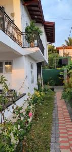 a white house with a balcony and a walkway at Dee Holidays in Moratuwa