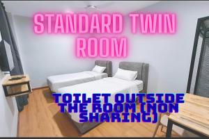 a room with two beds and a pink sign on the wall at KM Barakah Suite Kuala Terengganu in Kuala Terengganu