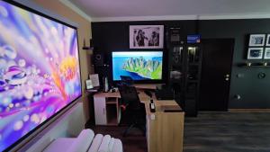 a living room with a large screen tv and a desk at Zagora Hills Premium Apartman in Krapina