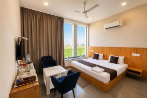 a hotel room with a bed and a desk and a window at Hotel Olive Sunny Enclave, Near Airport Road, Mohali in Kharar