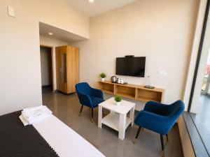 a hotel room with two blue chairs and a tv at Hotel Olive Sunny Enclave, Near Airport Road, Mohali in Kharar +22 photos