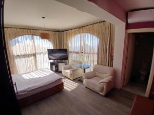 a bedroom with a bed and two chairs and a tv at Zone Guest House Bellapais in Kyrenia