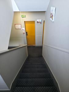 a hallway with a staircase with a yellow door at The Originals City, Hôtel Le Savoy, Caen in Caen