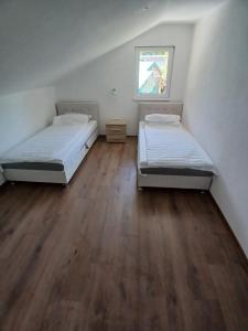 two beds in a room with a wooden floor at Apartman Nature in Konjic
