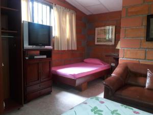 a living room with a couch and a television at Cabañas La Honda in Guatapé