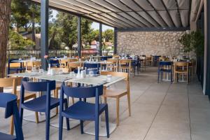 a restaurant with white tables and blue chairs at Family Hotel Adria - All inclusive in Biograd na Moru