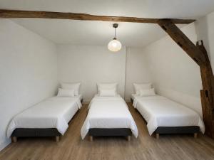four beds in a room with white walls and wooden floors at Maison de ville hypercentre Béthune in Béthune