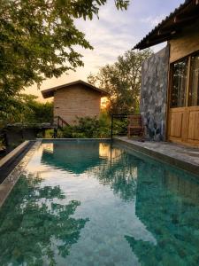 a swimming pool in front of a house at J Villa Sigiriya - Private Pool Chalets in Dambulla