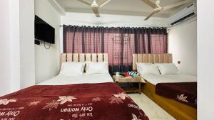 a bedroom with two beds and a tv in it at Hotel New Kalabagan in Dhaka