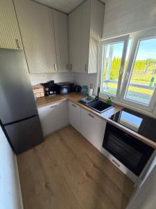 a small kitchen with a refrigerator and a sink at Domki u Izabeli niedaleko Darłowa in Rusko