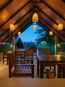 a patio with wooden tables and chairs and lights at J Villa Sigiriya - Private Pool Chalets in Dambulla