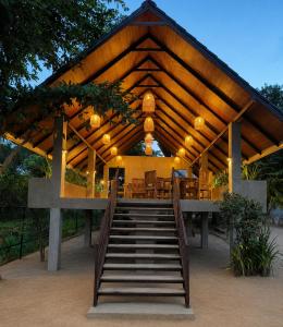a pavilion with a staircase leading to a table and chairs at J Villa Sigiriya - Private Pool Chalets in Dambulla