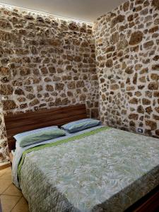 a bed in a room with a stone wall at Cavour 92 in Alatri