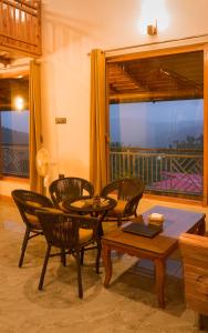 a living room with a table and chairs and a balcony at Pine Grey Castle in Almora