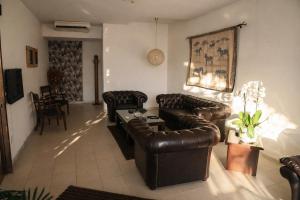a living room with leather couches and a table at Manuella Hotel in Ed Dkârîne