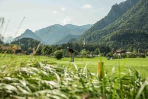 a man is playing golf on a golf course at Hotel Garni Forsthaus Ruhpolding incl Chiemgau Karte in Ruhpolding