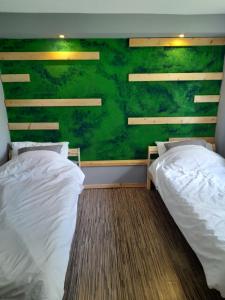 two beds in a room with a green wall at Malwers in Zielonka