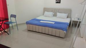 a bedroom with a bed with a blue blanket and a chair at RelaxAlkhuwirHostel in Muscat
