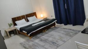 a bedroom with a large bed with blue curtains at RelaxAlkhuwirHostel in Muscat