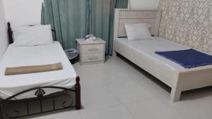 a bedroom with two beds and a nightstand and sidx sidx sidx sidx at RelaxAlkhuwirHostel in Muscat